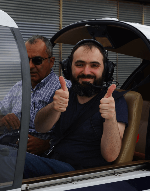 Lionel giving a thumbs up while seated in a plane