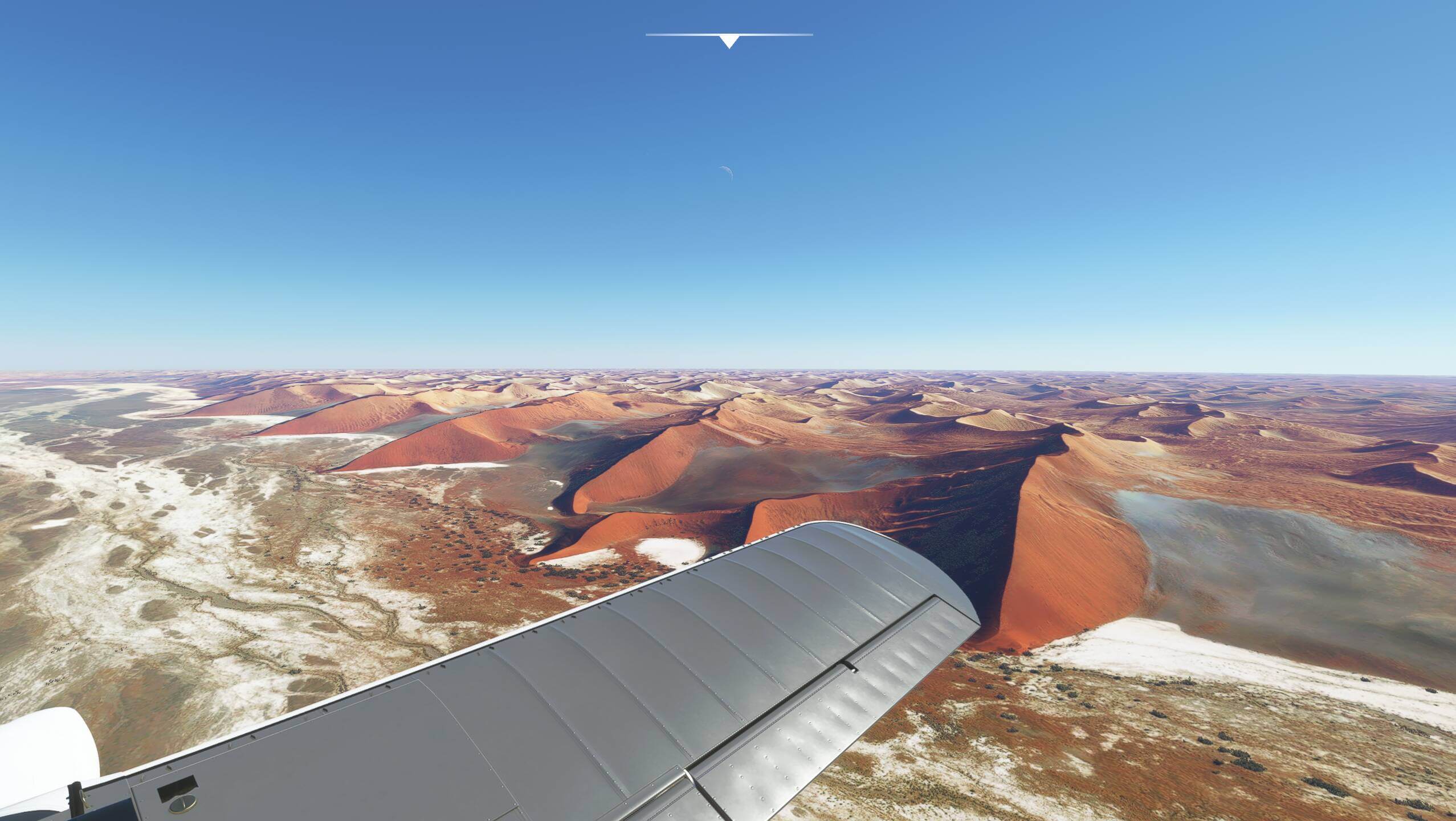 Plane wing view over desert dunes