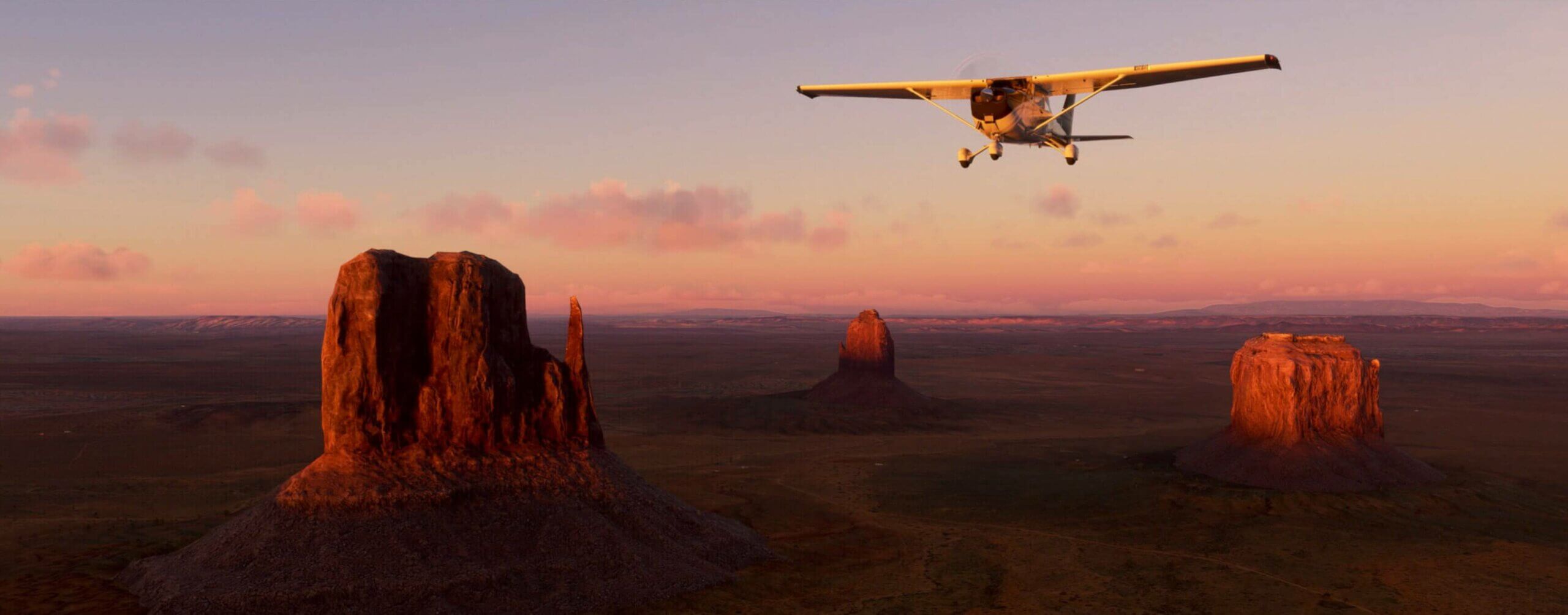 A plane flies over monument valley