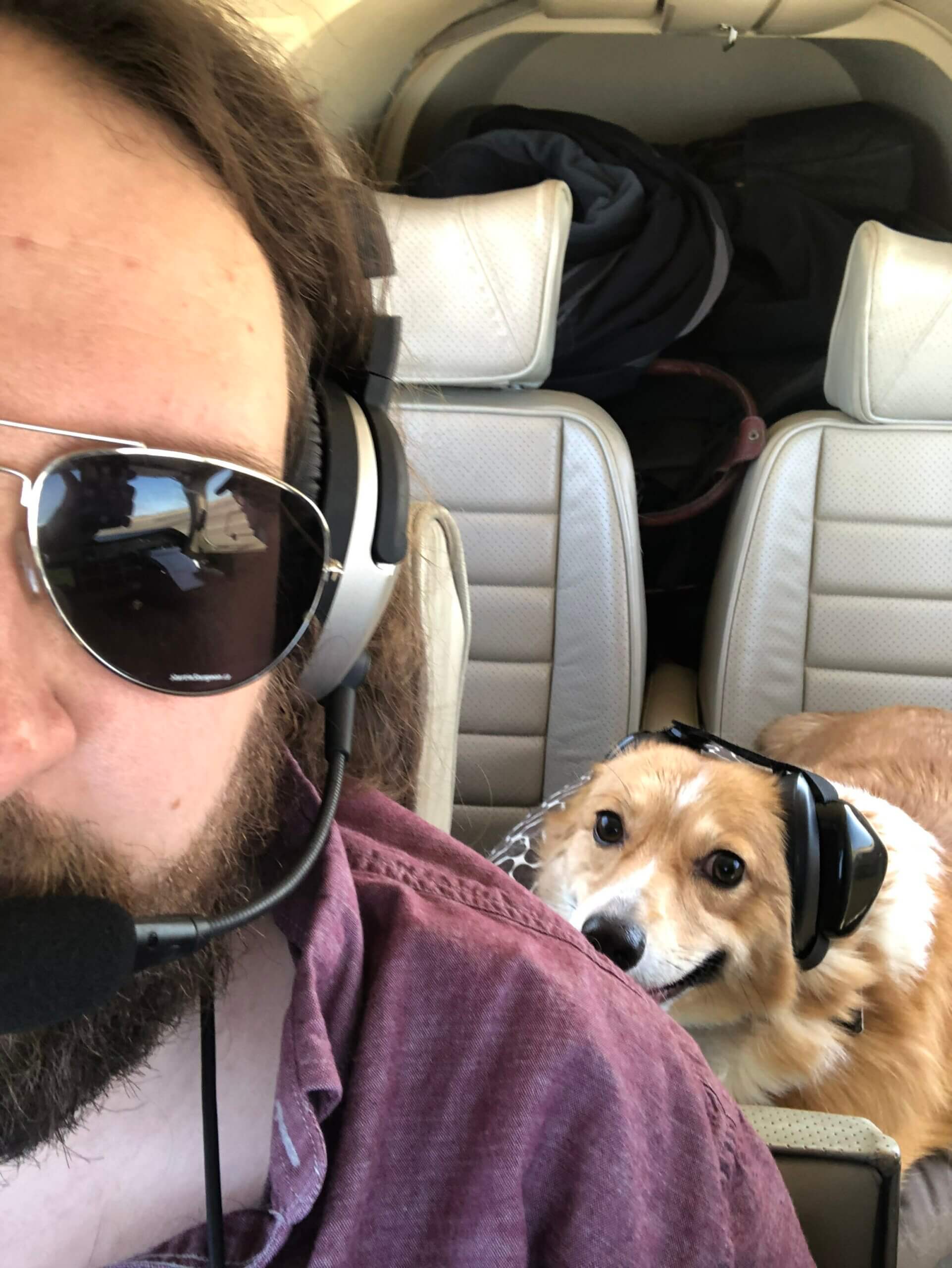 A man and a dog are in the cockpit of a plane