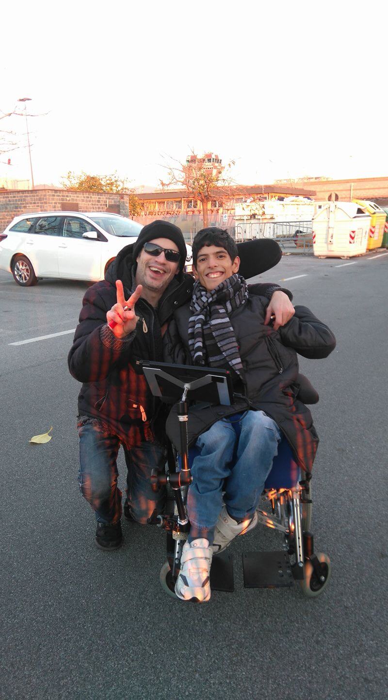 Roberto, left, flashes a peace sign while kneeling next to Lillo, right, in his wheelchair