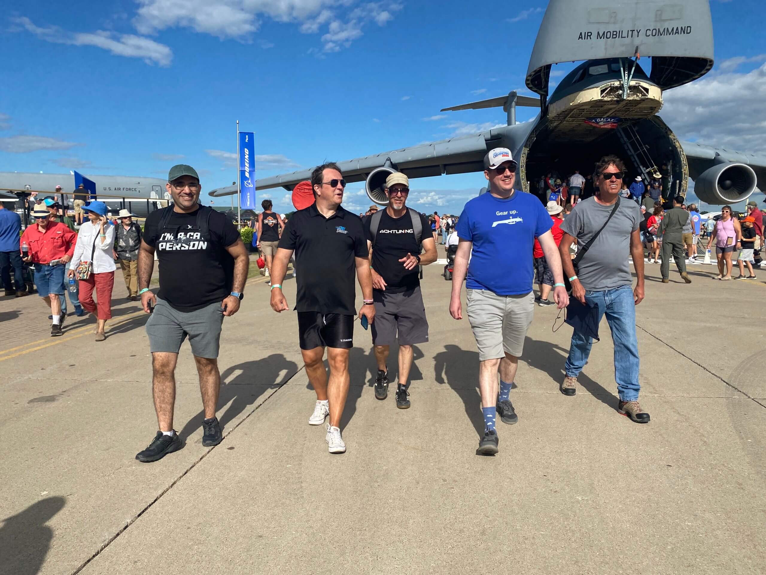Members of the Microsoft Flight Simulator team walk towards the camera with a C-5 Galaxy military transport plane in the background