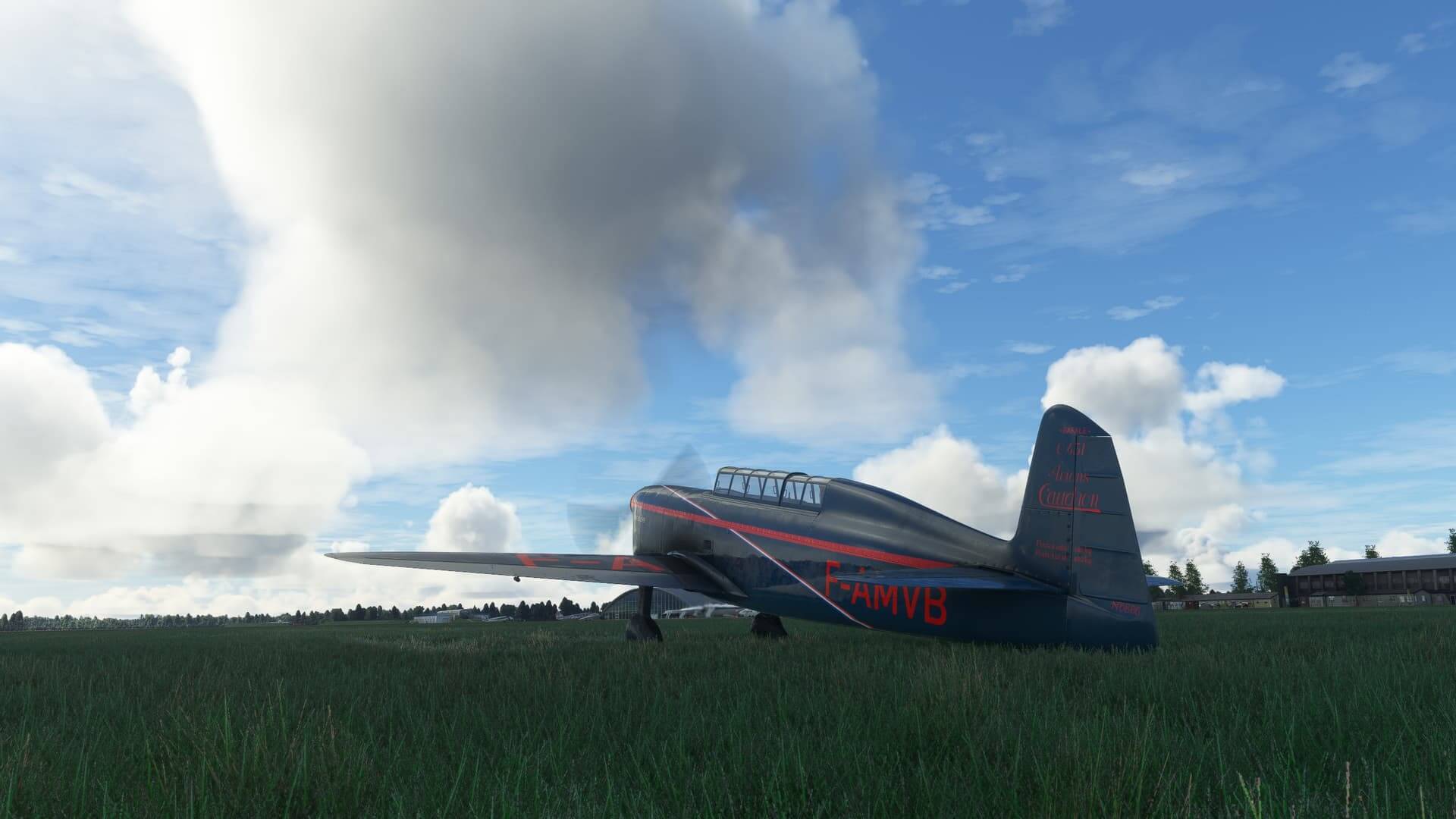 A grey and red plane sits parked in a sunny field.