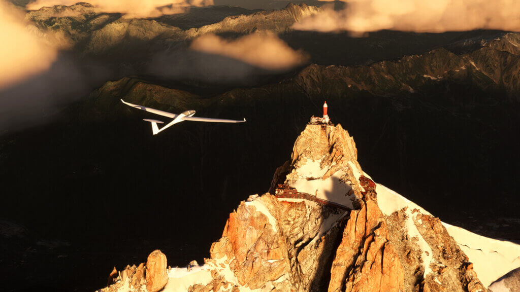A glider flies overtop a mountain observatory, lit by the morning light.