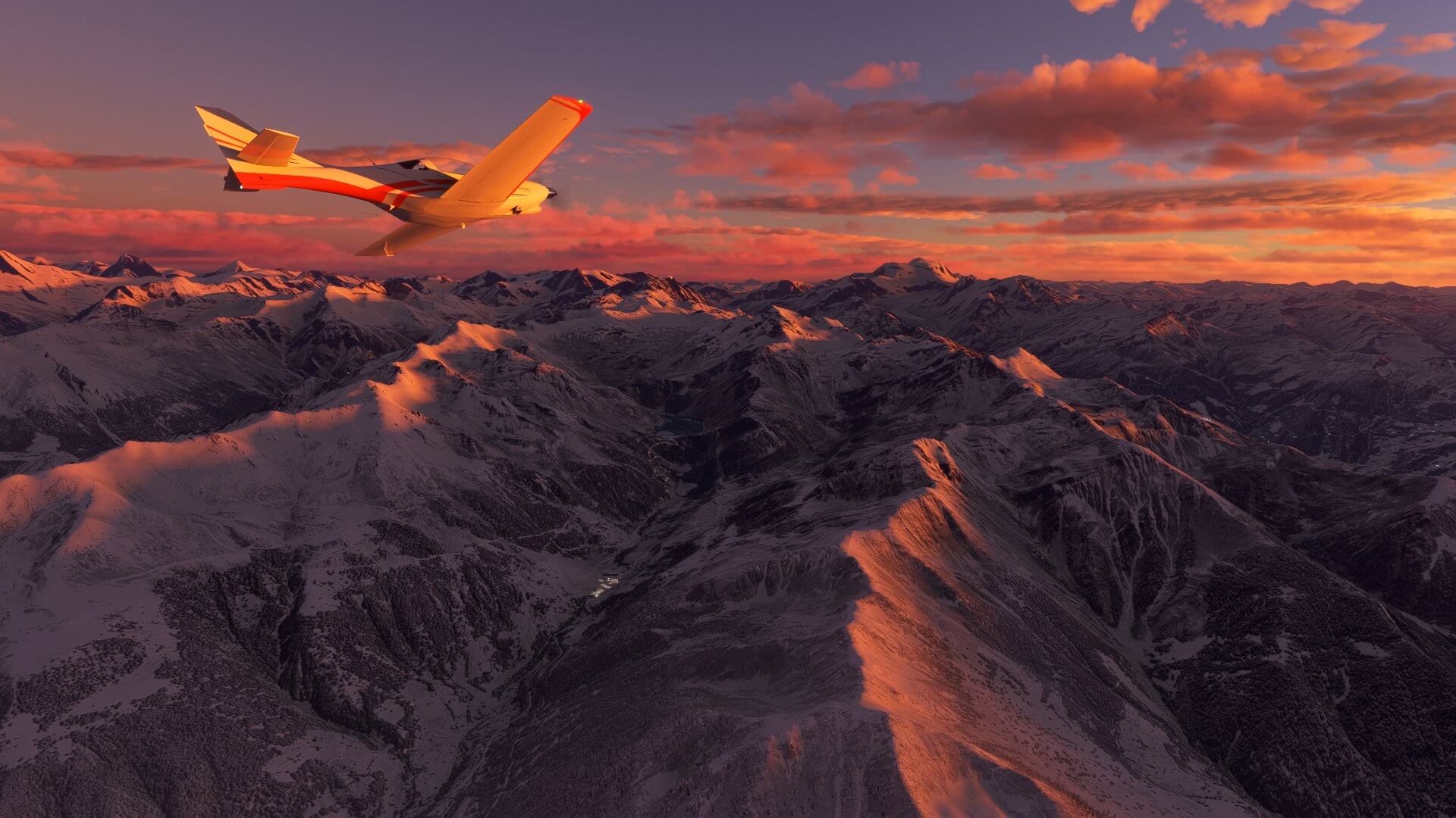 A plane flies over mountains lit in pink by the setting sun.