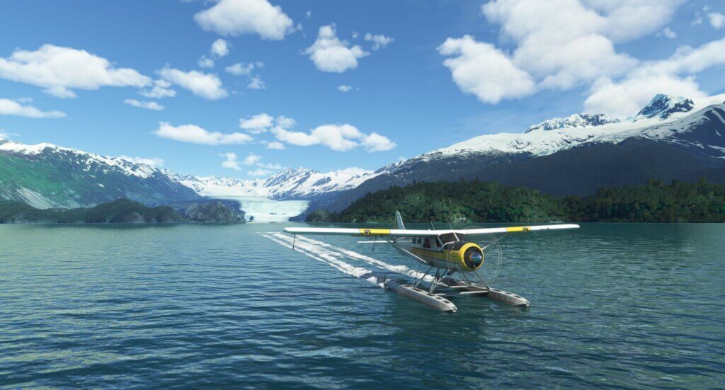 A floatplane skids to a stop on the water in front of some snowy mountains