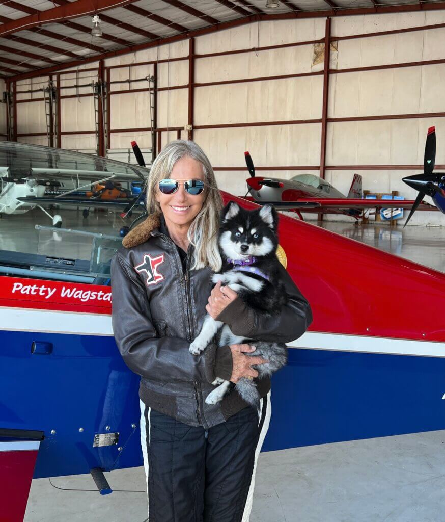 Patty and her dog in front of a plane