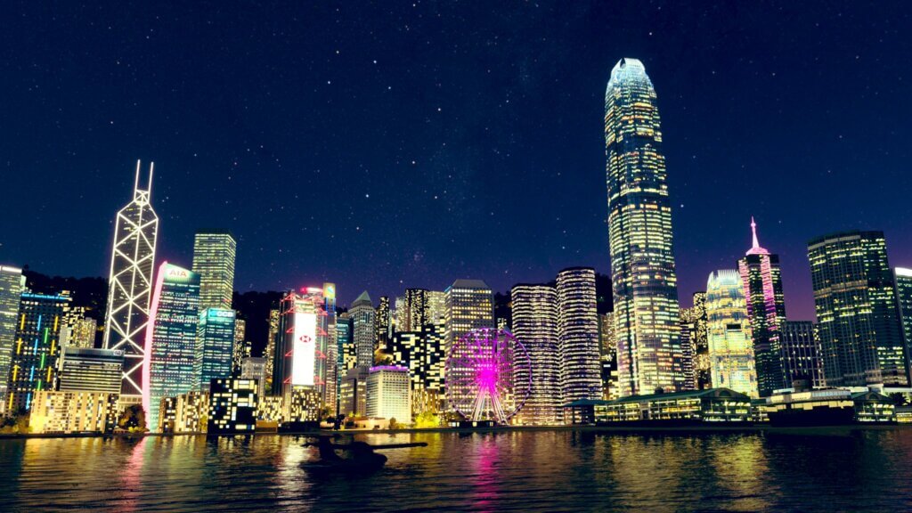 An ICON A5 is floating in Hong Kong's Victoria Harbour at night. Several famous buildings are lit up and visible, including the Bank of China Tower and the International Finance Centre.