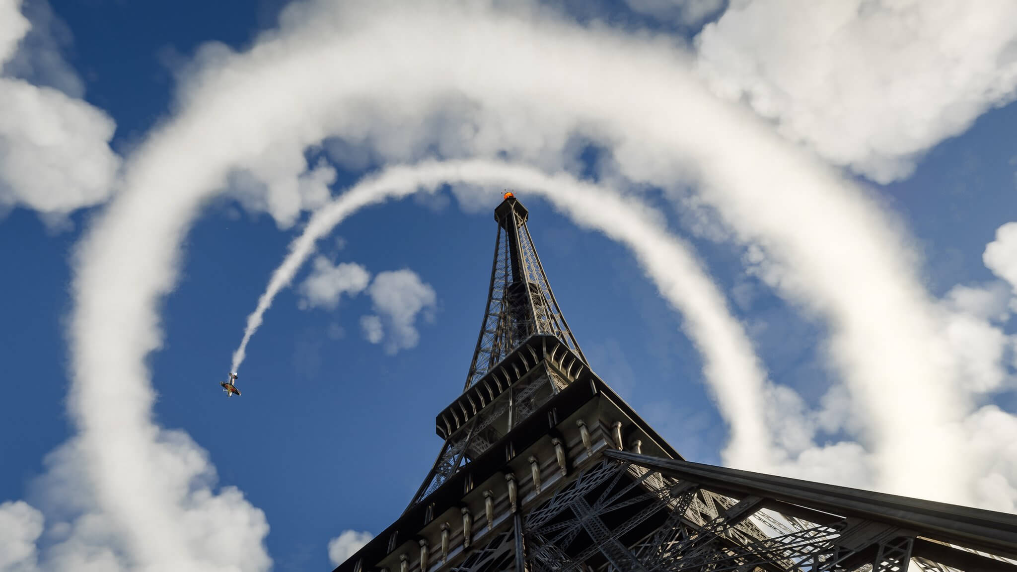 An Extra 330LT with aerobatic smoke turned on flies in a spiral pattern around the Eiffel Tower.