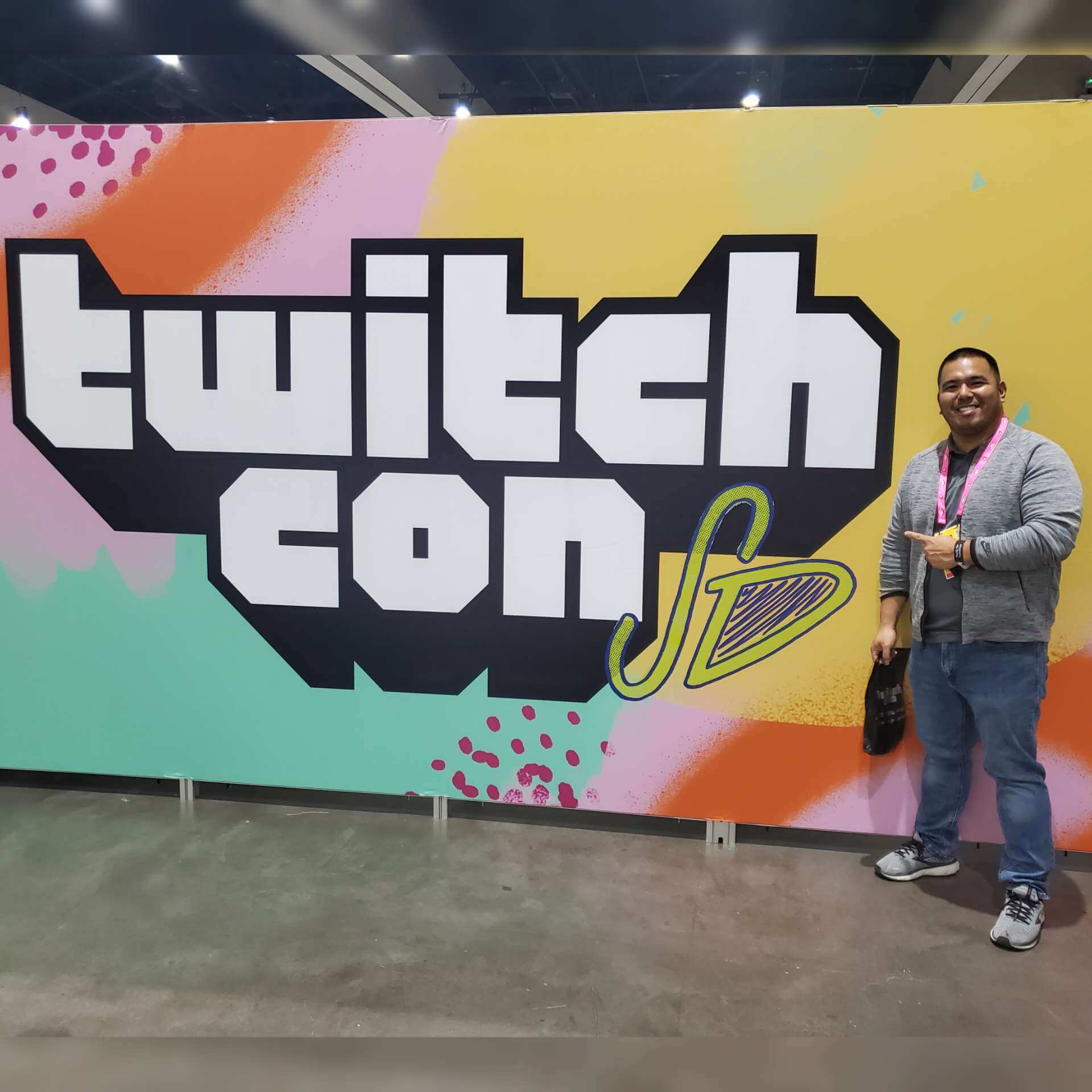 JoeyBolo77 stands in front of a banner for Twitchcon 2022 in San Diego.