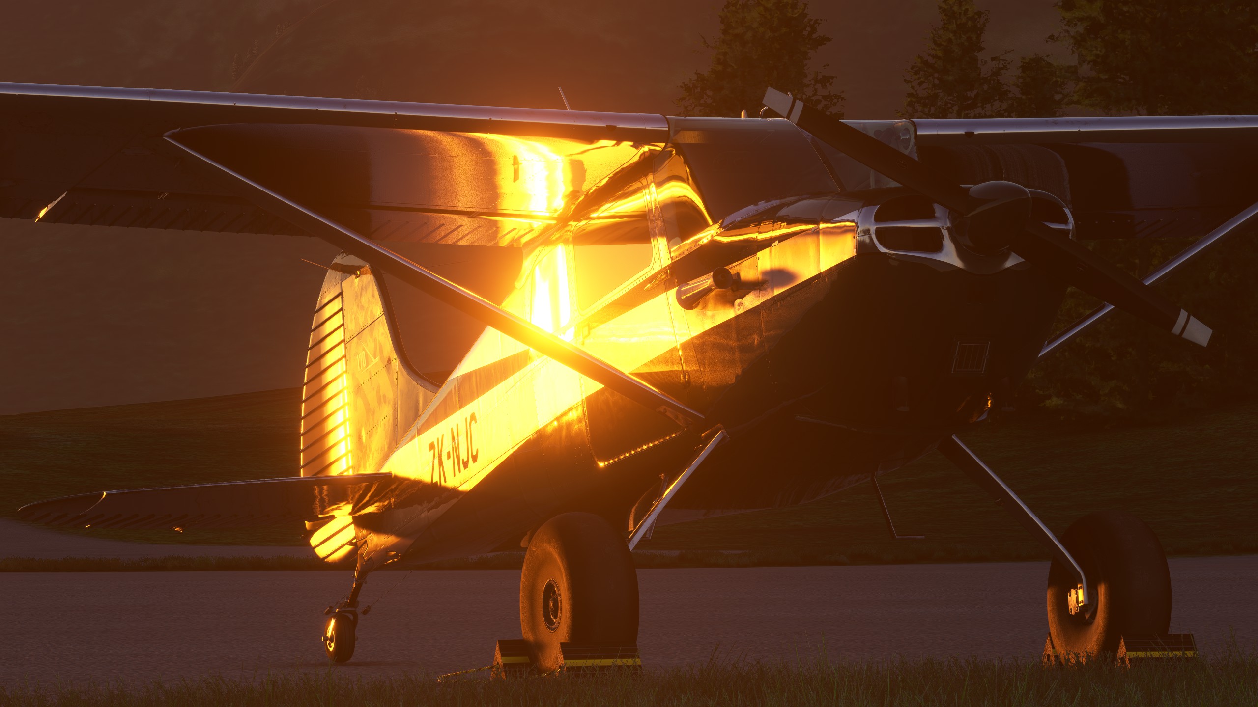 A high wing taildragger GA aircraft is parked on the ground. The sun is reflecting off the side of the plane.