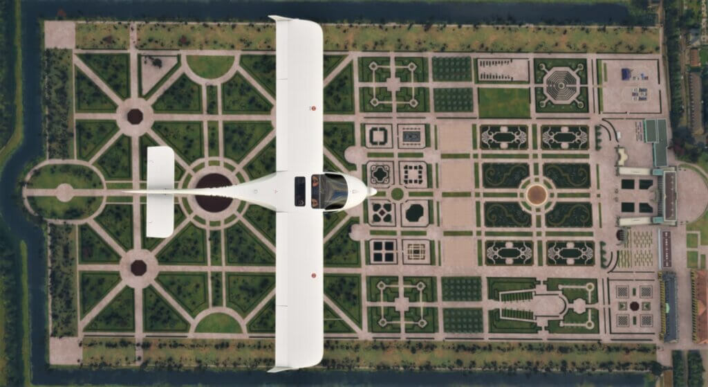 Top-down view of a Diamond DA40 flying over an elaborate garden with many geometrical hedges.