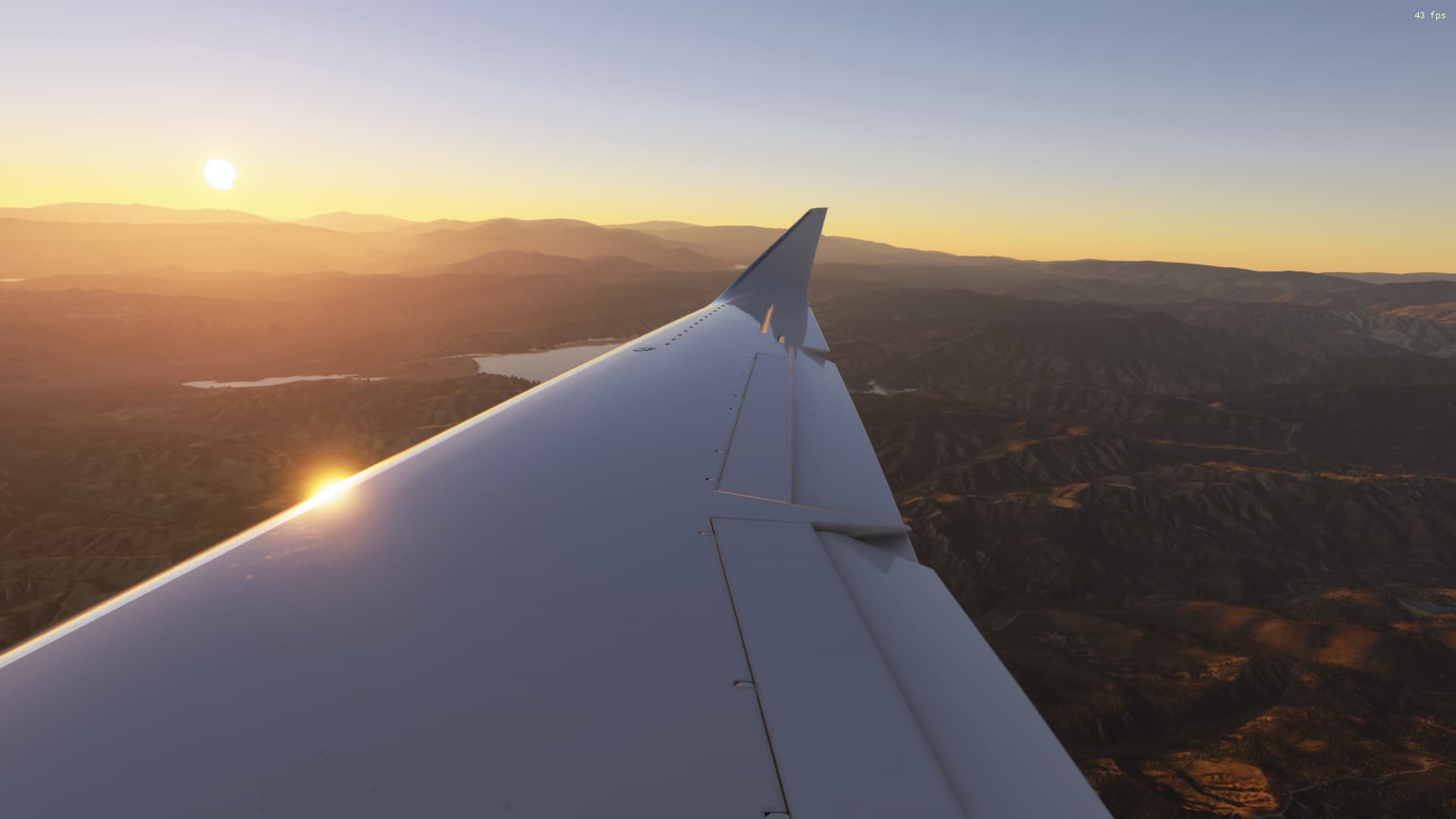 Looking out the window of an aircraft at its wing. In the horizon the sun is setting.