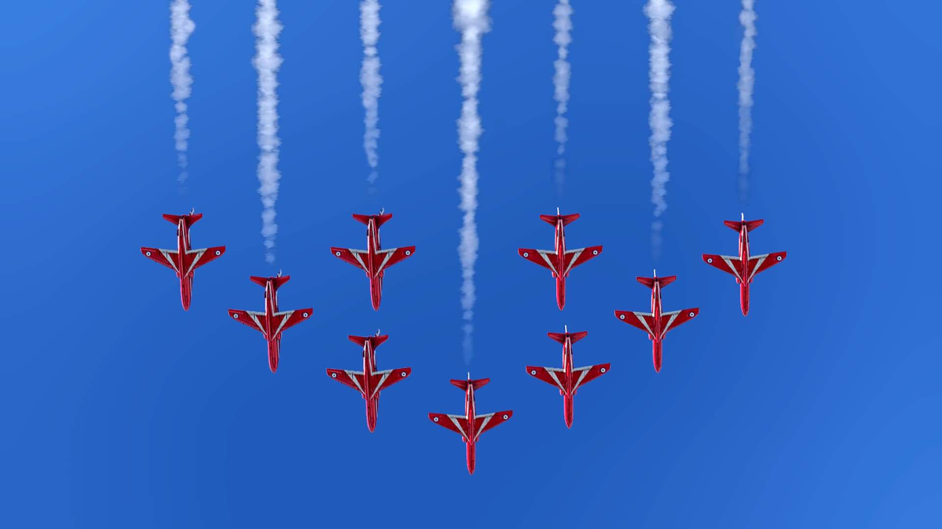 9 hawks of The Royal Air Force Aerobatic Team The Red Arrows fly in Vixen formation with white smoke plumes behind.