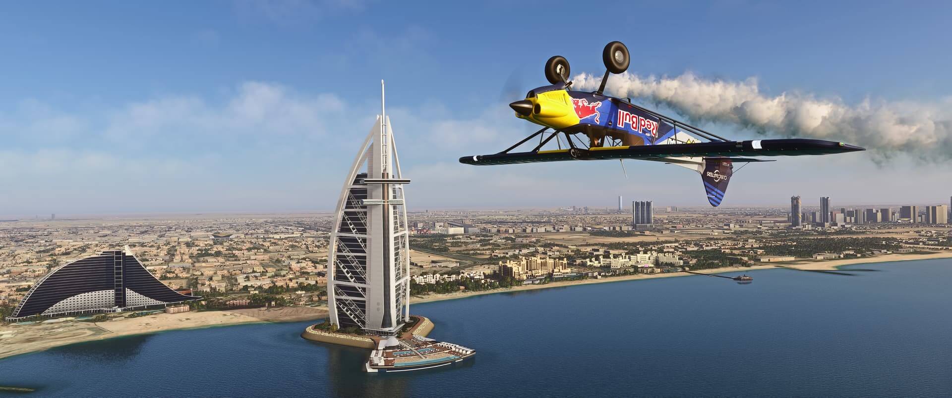 The Red Bull Carbon Cub flies inverted with white smoke trailing behind, whilst passing the Burj Al Arab Resort Helipad.