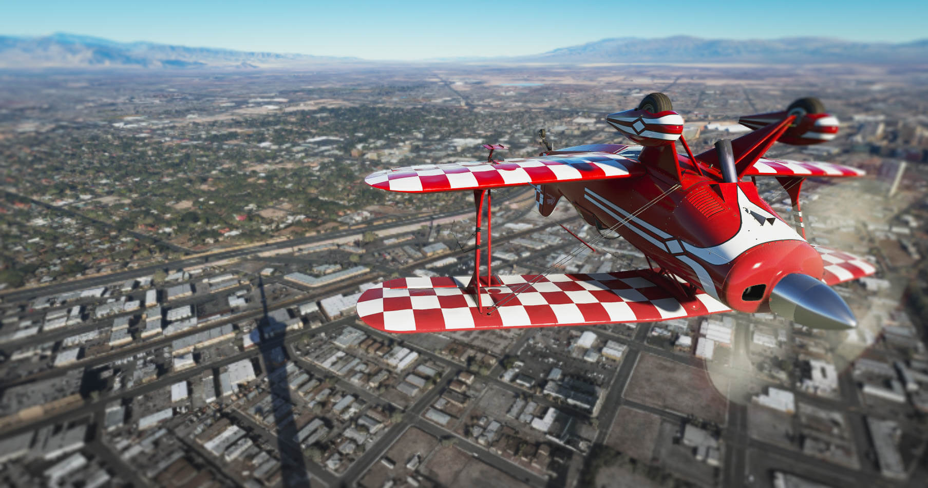 A red bi-plane aircraft passe over a city at low altitude inverted.