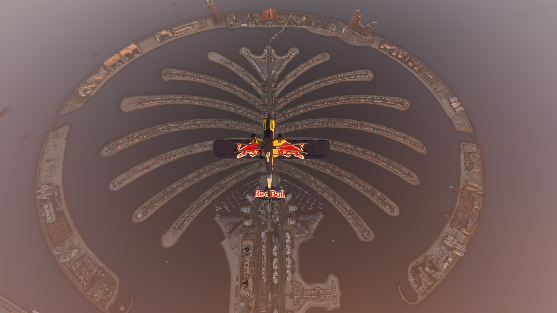 The Red Bull aerobatic aircraft perfectly frames a Palm Island in Dubai whilst flying inverted above.