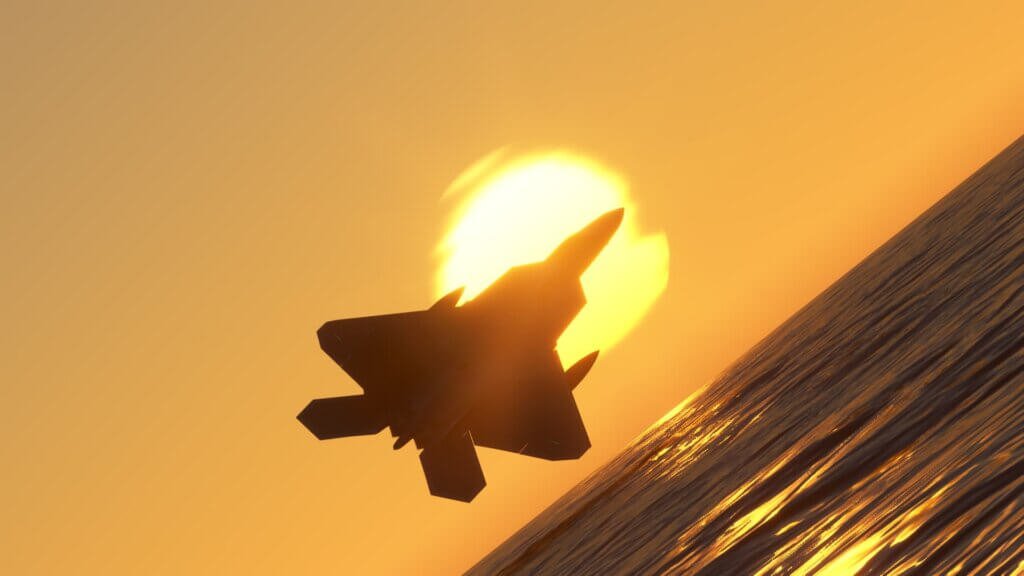 An F-22 silhouetted by the sun at golden hour does a knife edge pass above water.