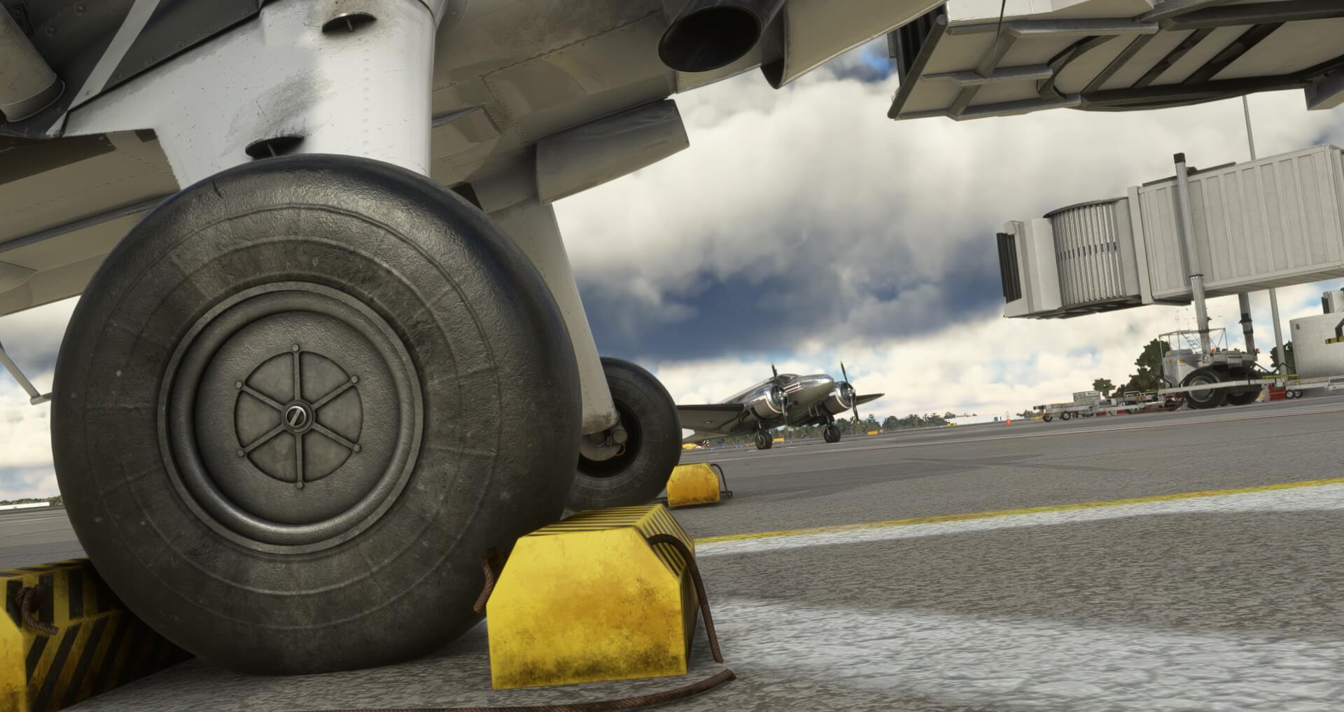 A close up shot of an aircrafts landing gear with chocks in place on the apron.