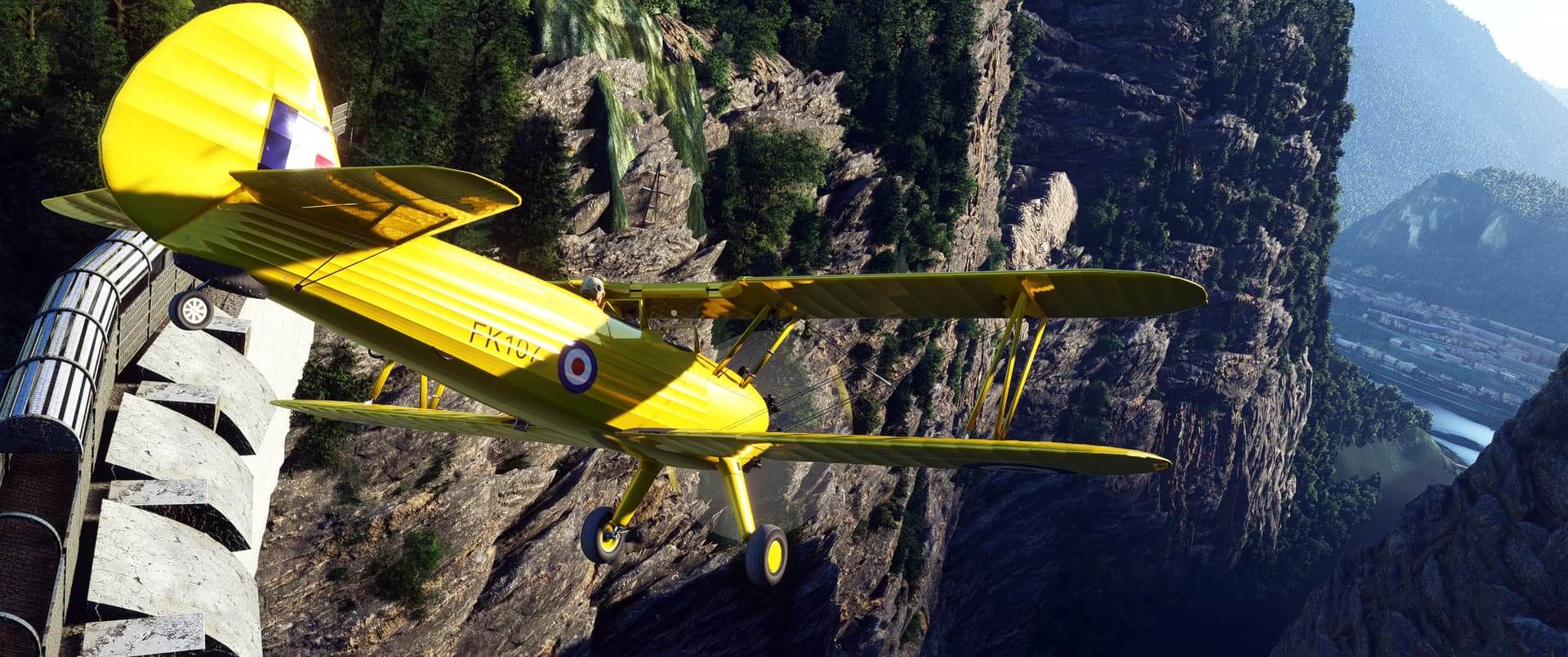 A yellow bi-plane dives into a valley with high terrain rising on either side.