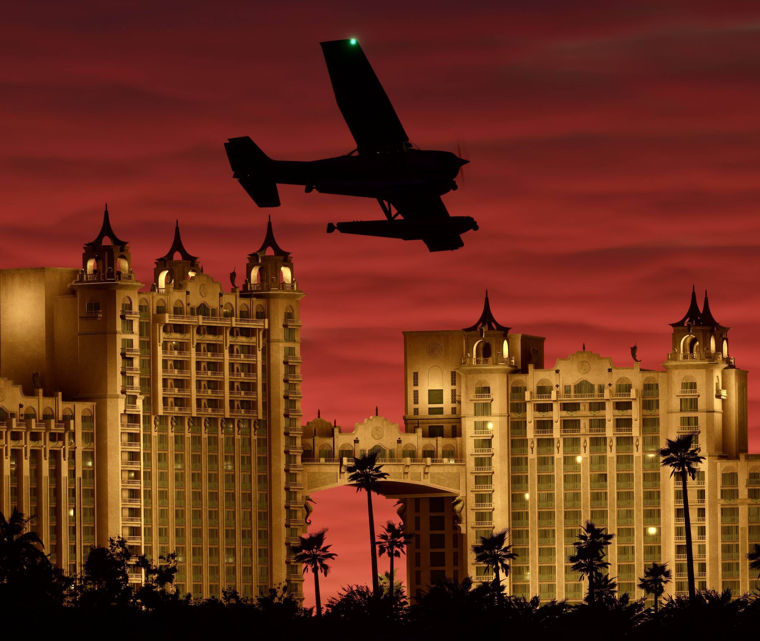 Red skies are cast behind the silhouette of an aircraft with high ride building lit up in gold behind.