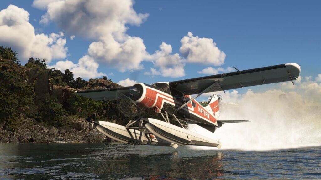 A water float propeller aircraft lifts from water with the rocky shore in view.