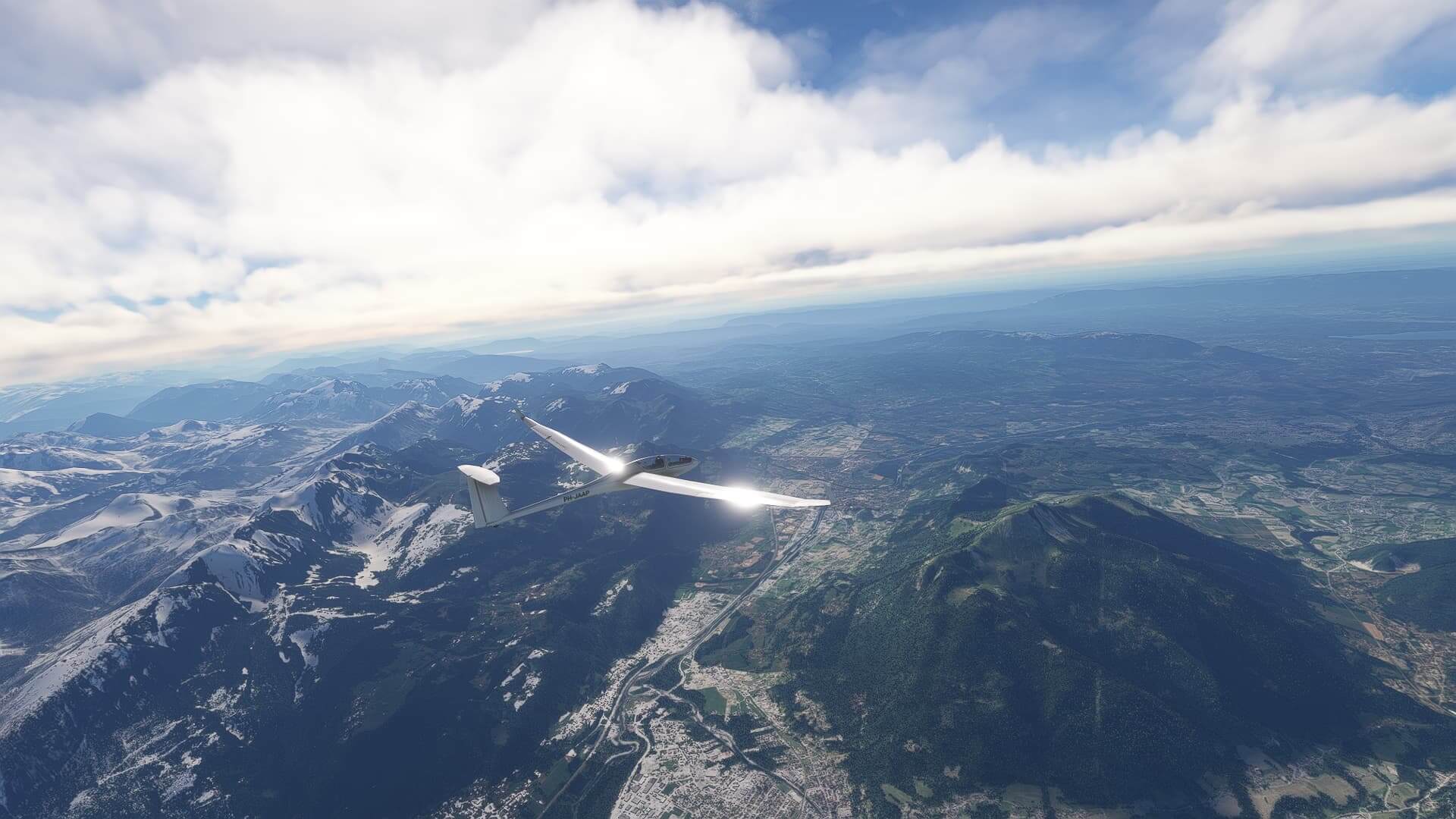 A Glider has the sun reflecting from its wings whilst cruising high above mountains.