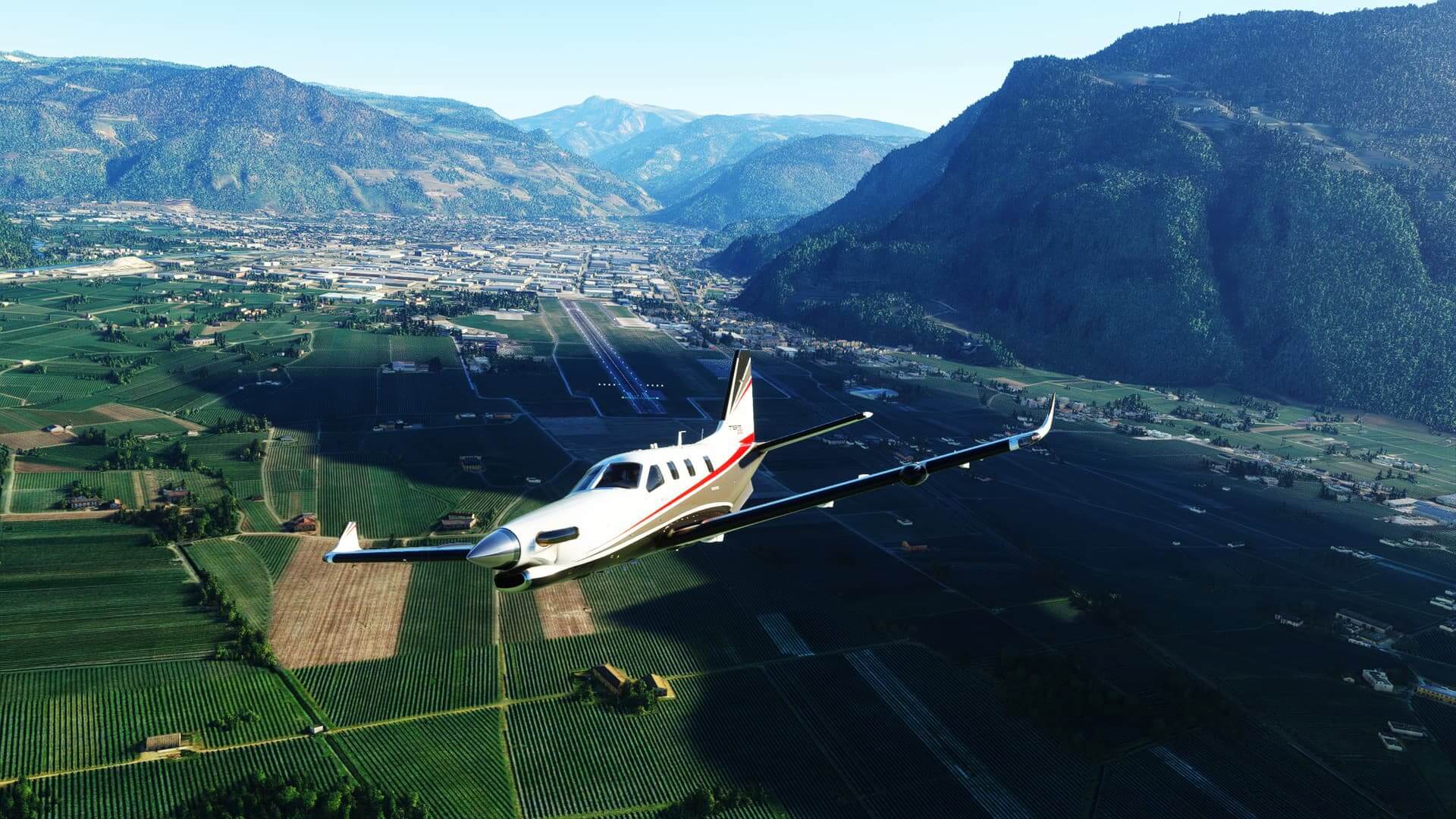 A TBM 930 banks left after taking off from an airport in a valley.