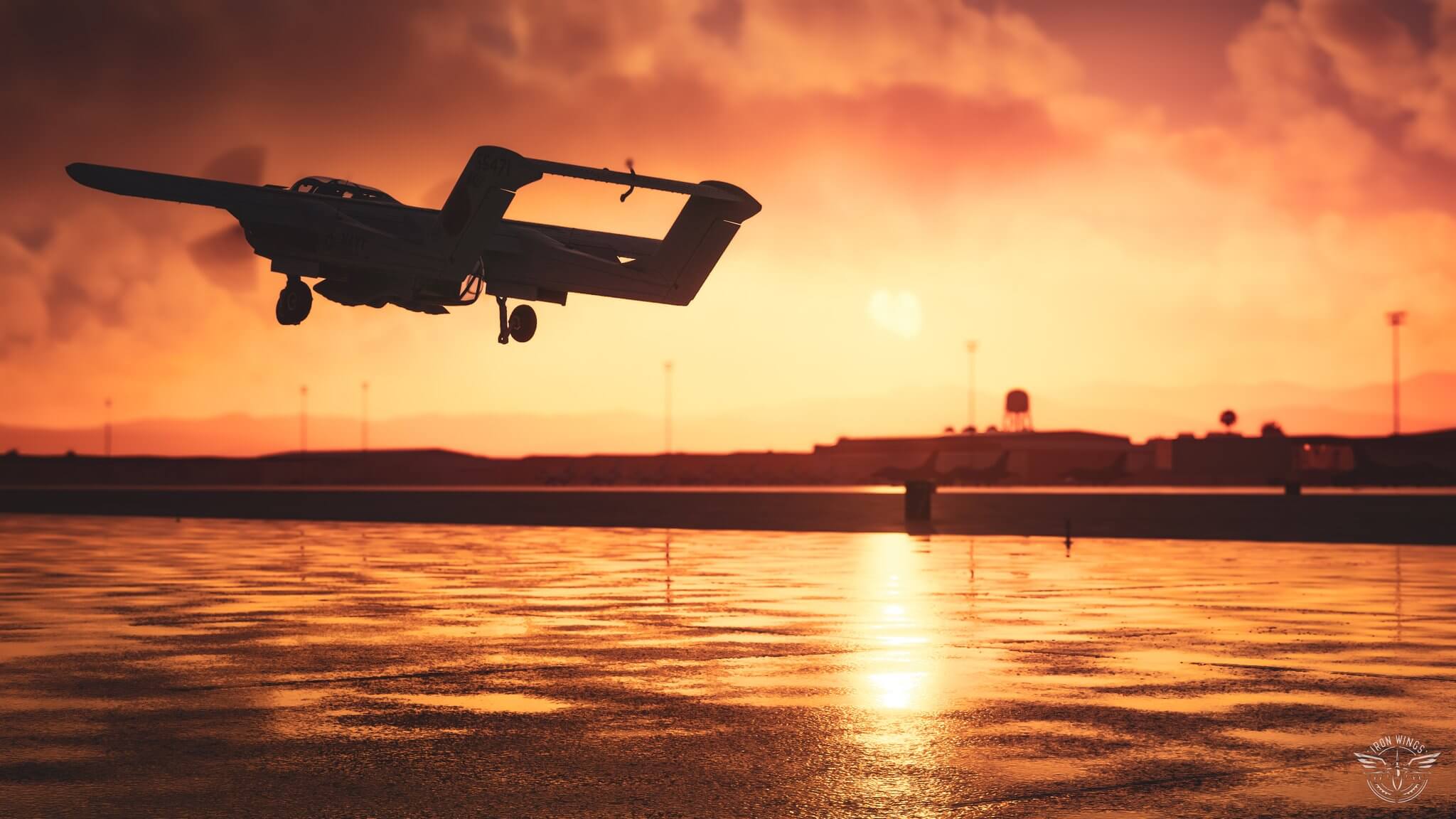 An OV-10 Bronco lifts off from a wet runway during golden hour, with the sun visible in the distance across the airport apron.