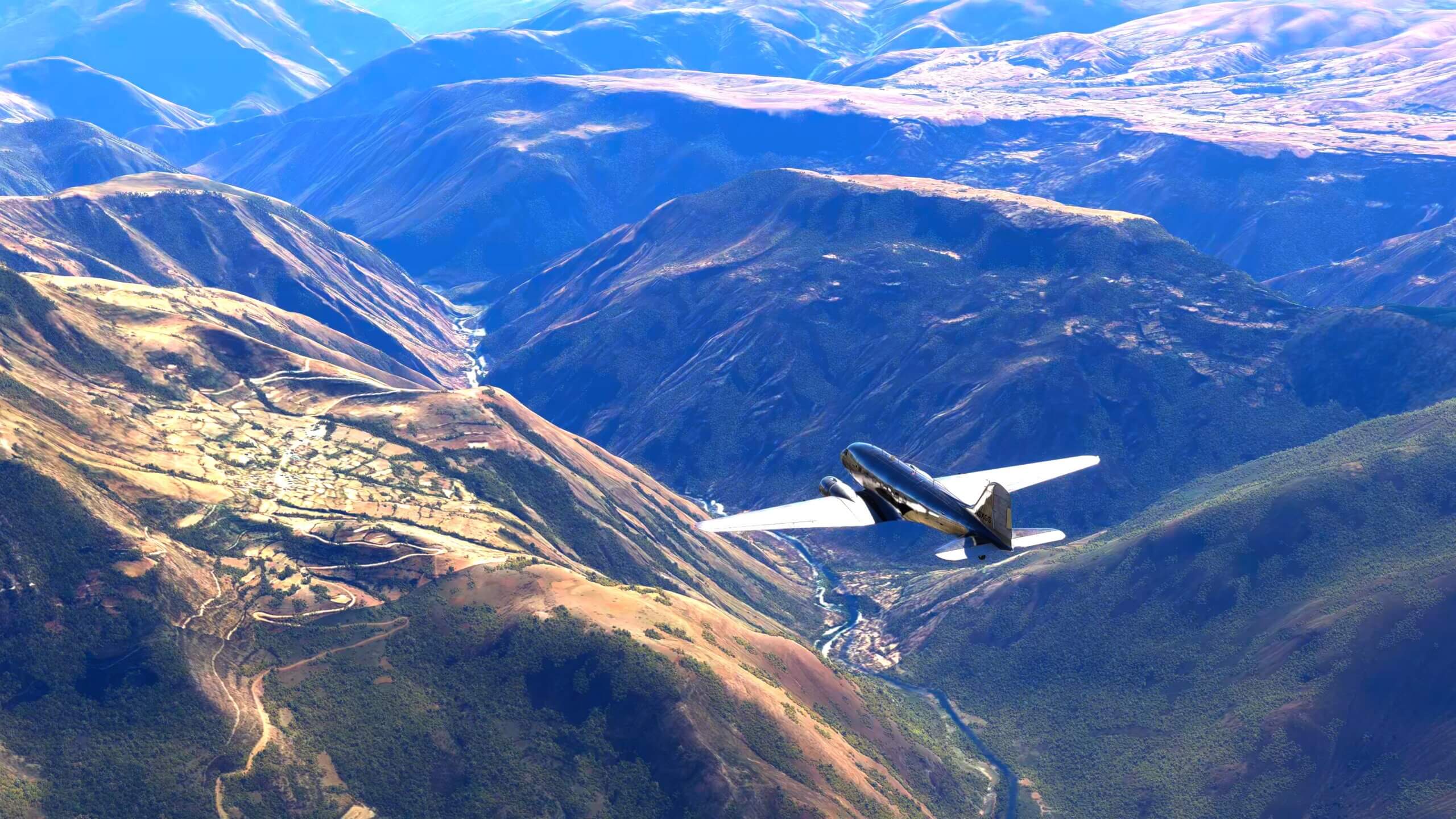 A DC-3 flies towards a valley in between high terrain, with a river flowing through the valley below