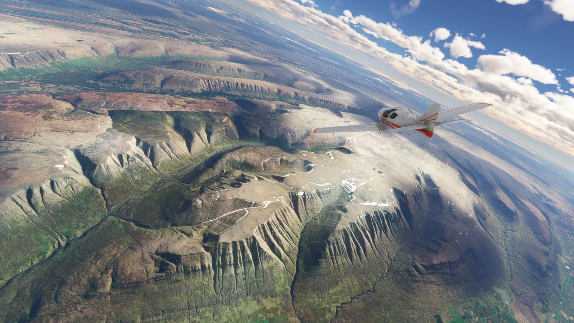 A low-wing general aviation aircraft in red and white paint scheme banks left whilst flying over mountains