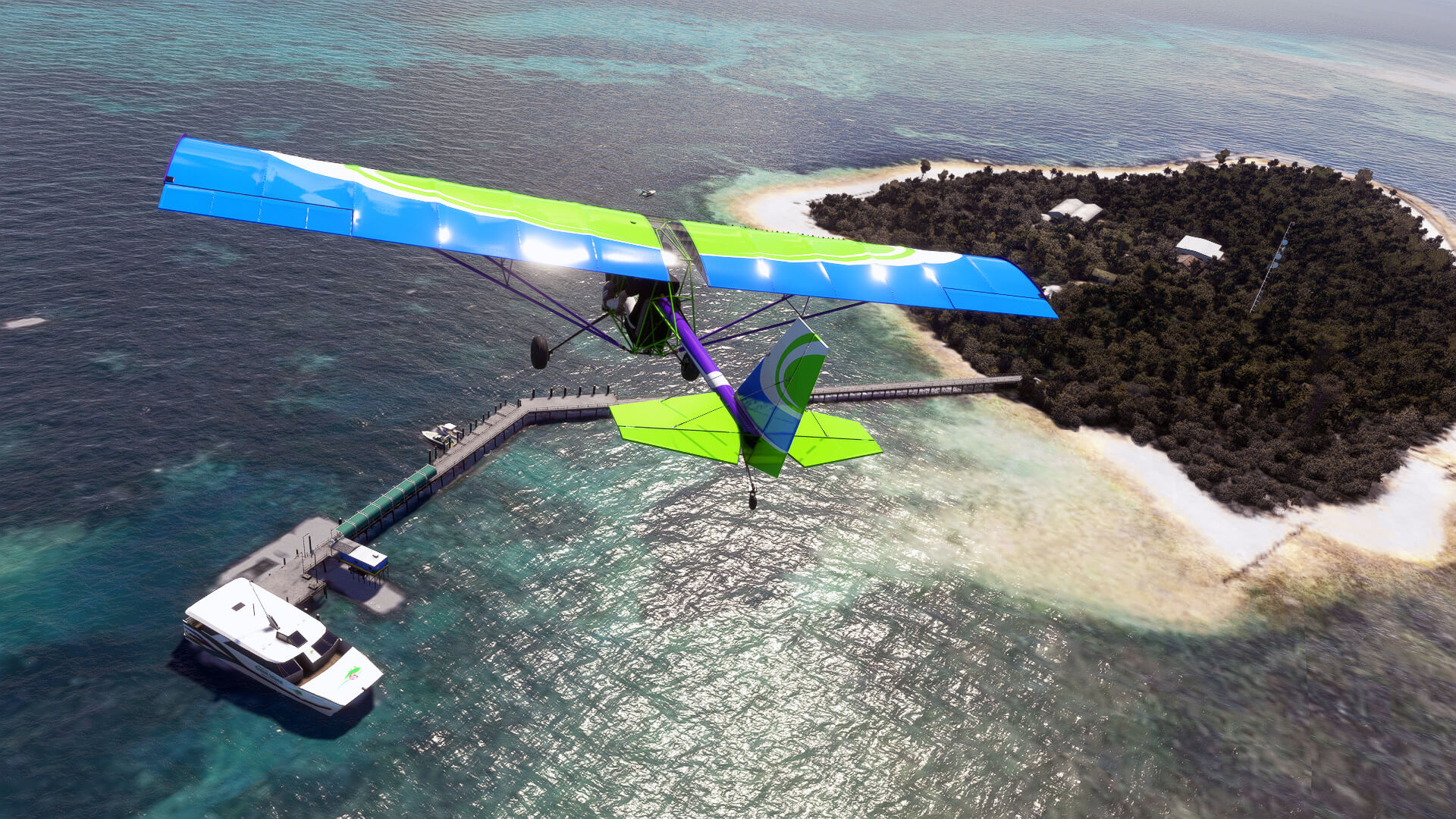 A blue and green general aviation aircraft flies over an island marina, with a yacht moored up.
