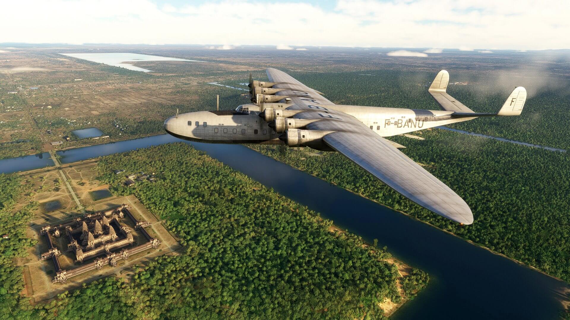 A Latécoère 631 flies over an ancient monument with the sun reflecting brightly off of its fuselage and wings