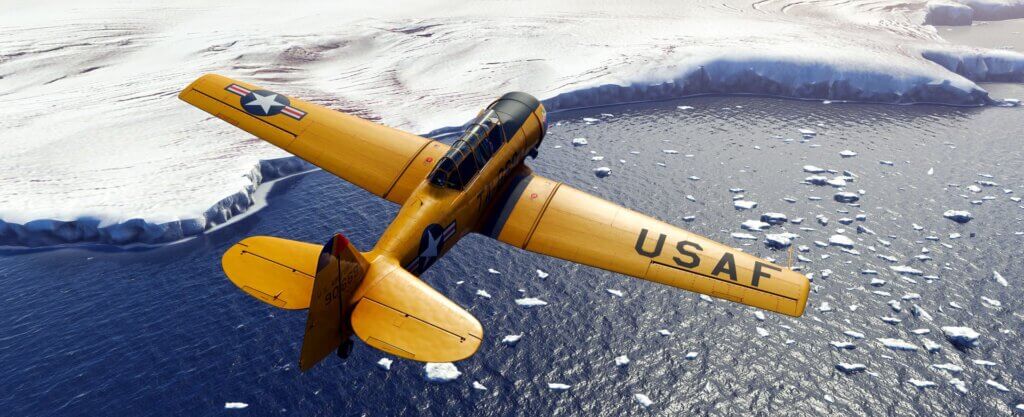 A T-6 Texan in yellow US Air Force paint flies low to nearby icy glaciers