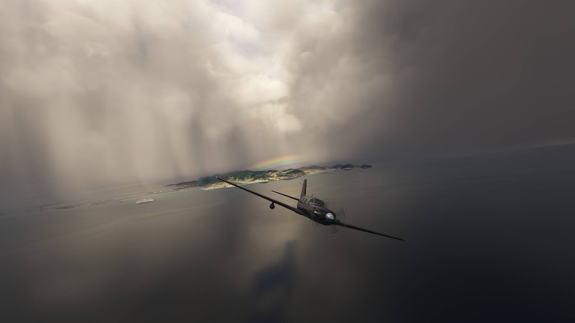A turbo prop in black paint scheme banks left whilst flying away from an island, with stormy clouds and a rainbow visible in the distance