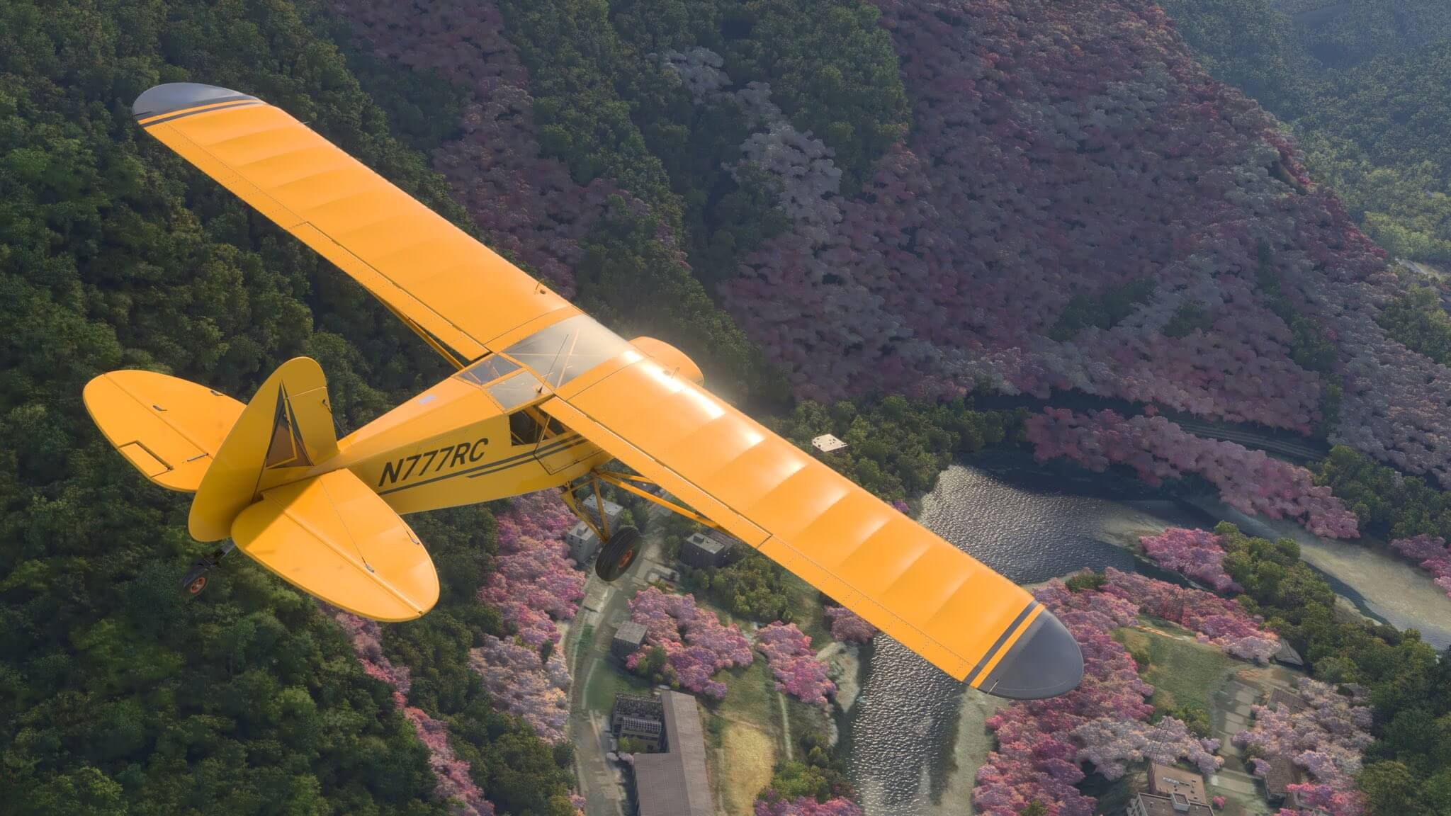 A yellow X-Cub flies high over mountainous cherry blossom trees