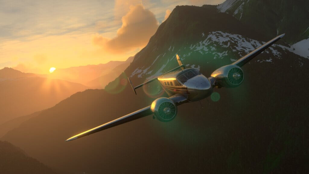 A twin engine propeller aircraft banks right whilst flying close to a mountain range, as the sun appears over the peak of a mountain behind