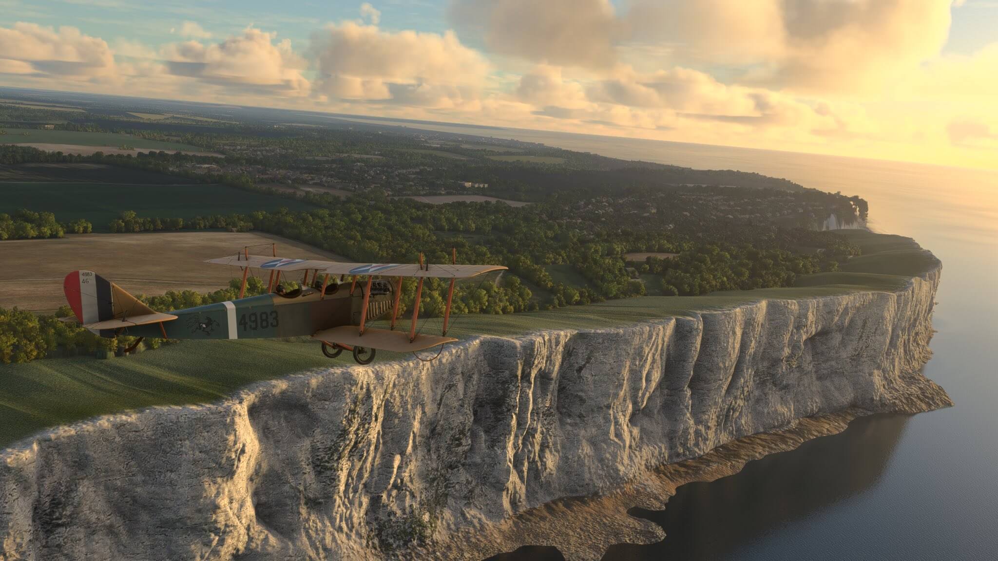 A Bi-wing propeller aircraft in military paint flies close to the white cliffs of Dover, England
