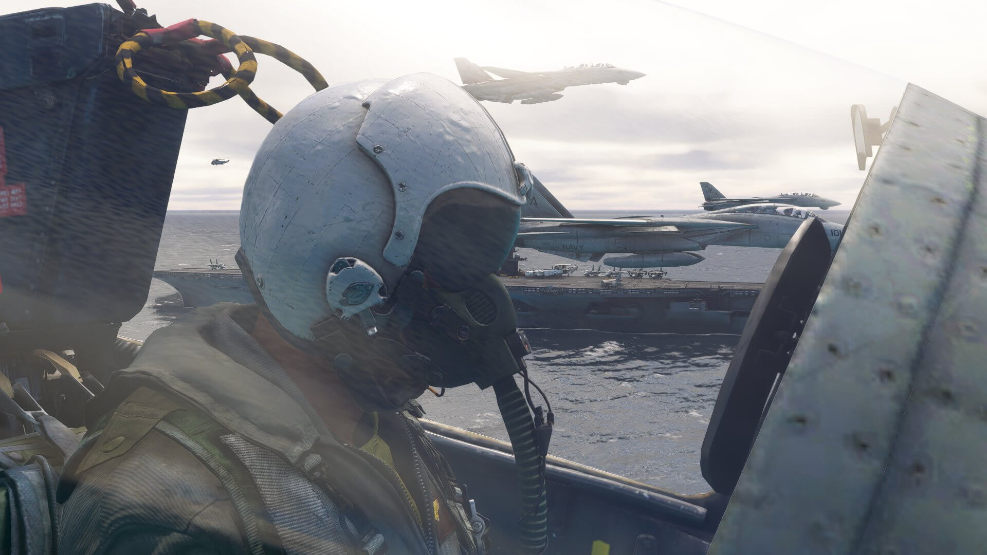 An F-14 pilot in helmet and breathing apparatus looks forward whilst in close formation with three other jets, passing low over an aircraft carrier