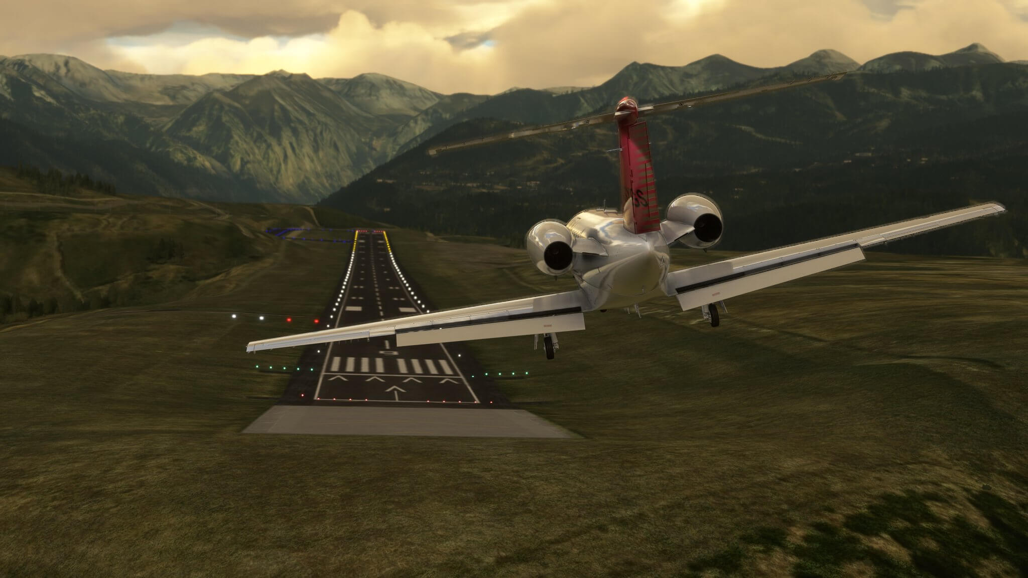 A Cessna Citation CJ4 banks left to line up with a sloped runway located in a valley.