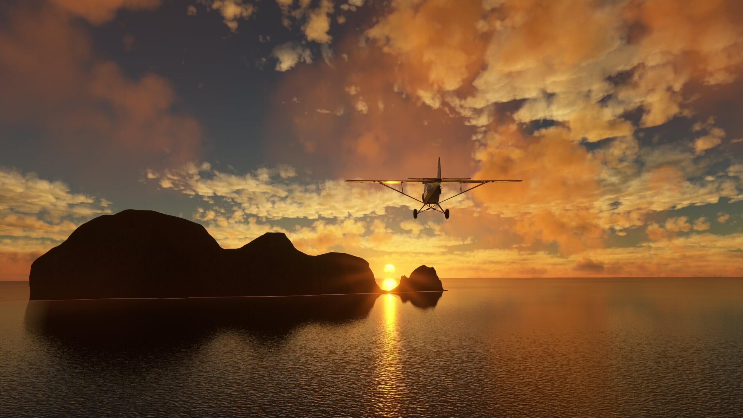 An X-Cub flies over water towards a rocky island with the sun shining through a gap in the terrain