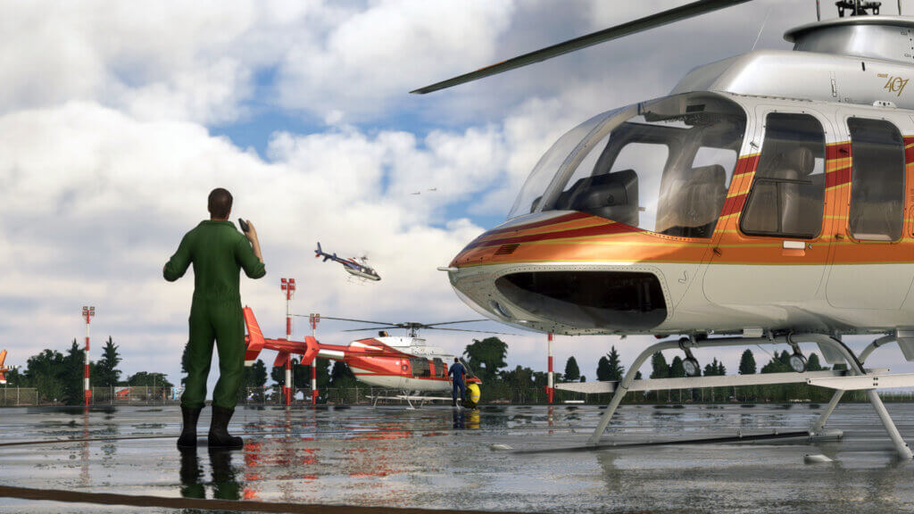 A pilot in green jumpsuit stands next to a Bell 407 on a helicopter apron, with other aircraft of the same type in the background.