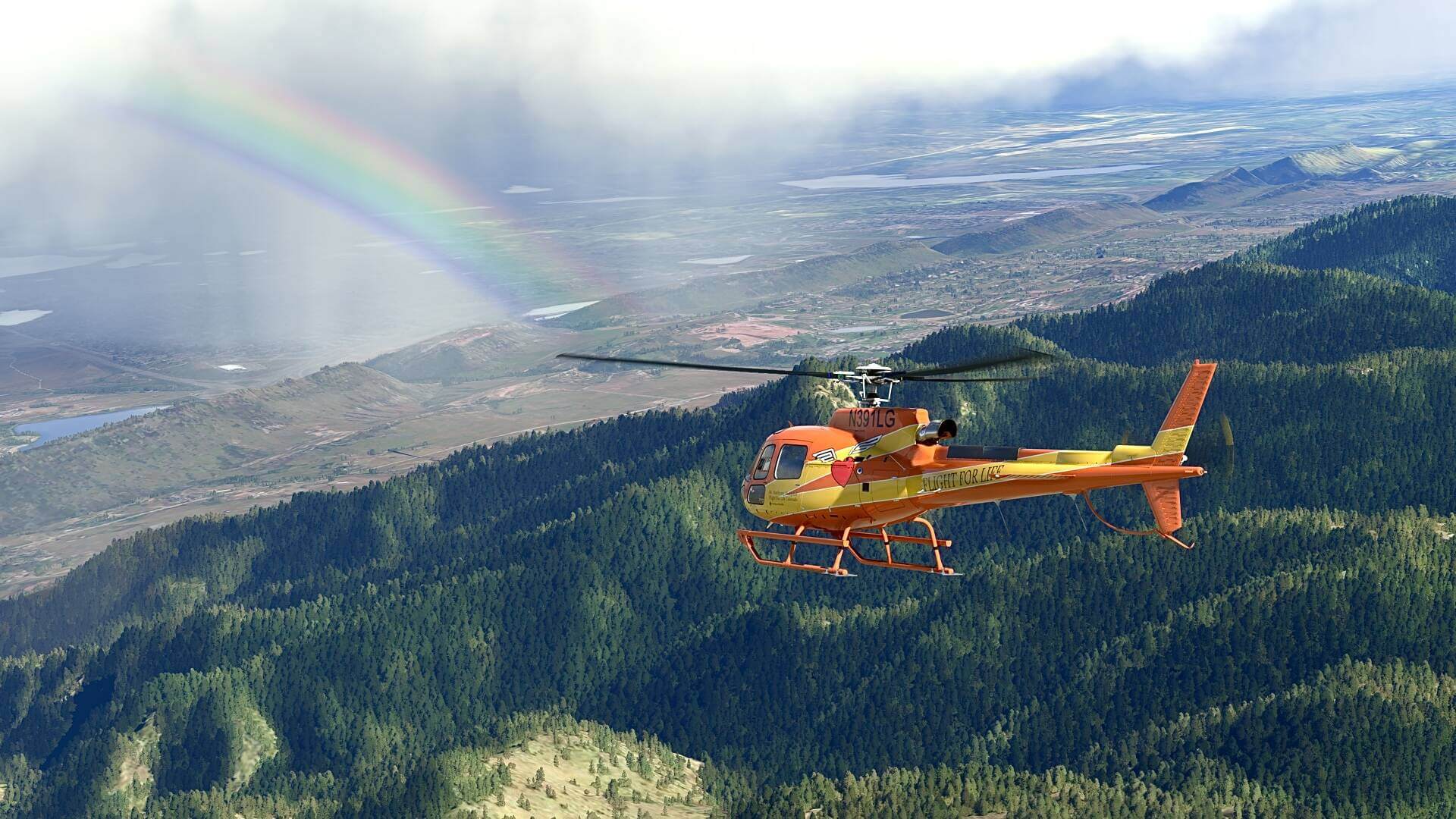 The H-125 helicopter in an orange and yellow livery scheme flies over a dense forest directly towards a rainbow