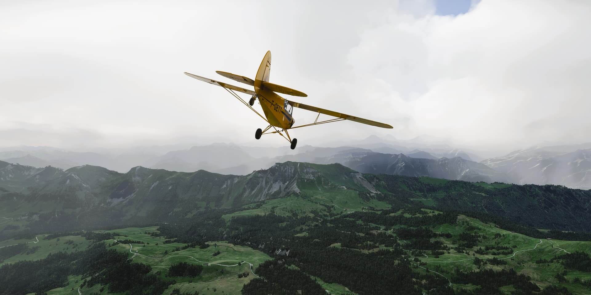 A yellow propeller aircraft flies towards a green mountain range, with limited visibility ahead due to a low cloud base