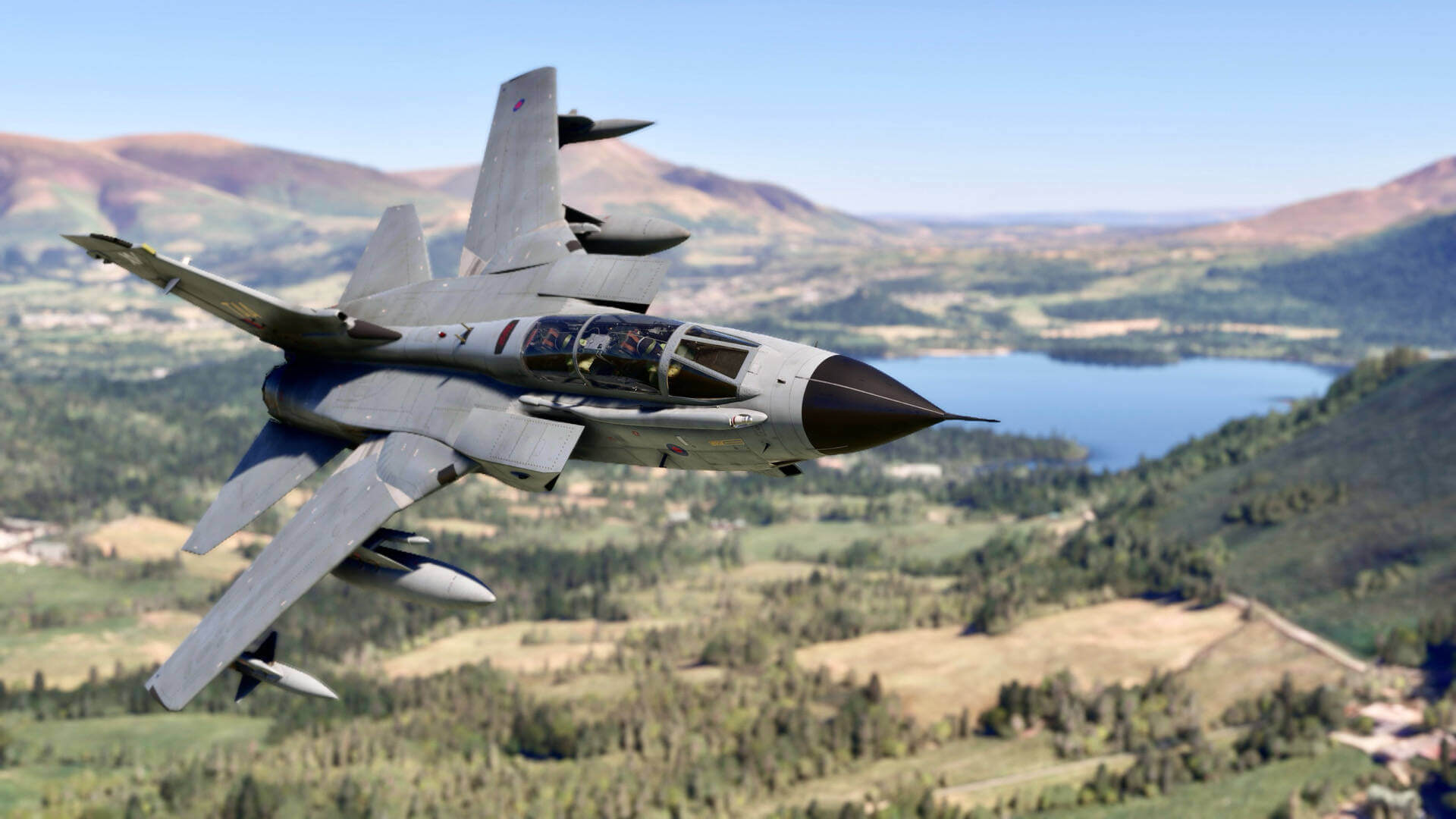 A Tornado fighter jet with wings spread banks sharply to the right whilst flying at low altitude in a valley