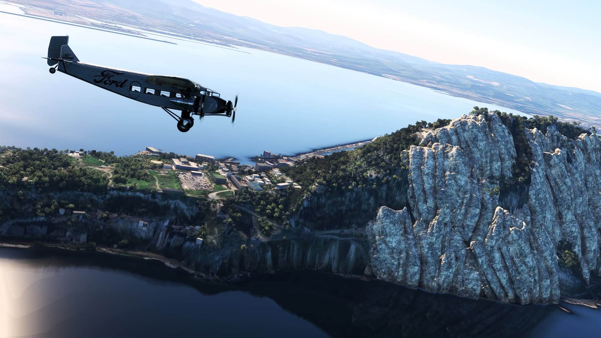 The Ford Tri-Motor cruises next to an island with rocky terrain in view off of the left wing