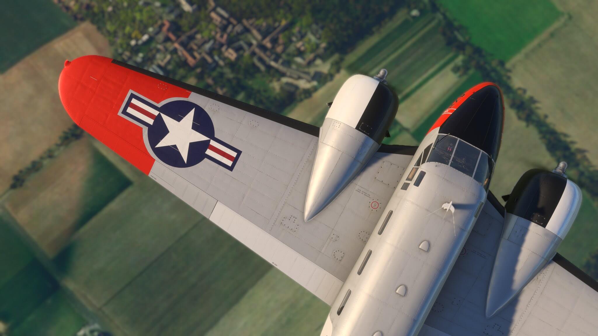 A US Navy dual propeller aircraft in grey, white, black, and red paint shown from a birdseye view flying overhead green fields.