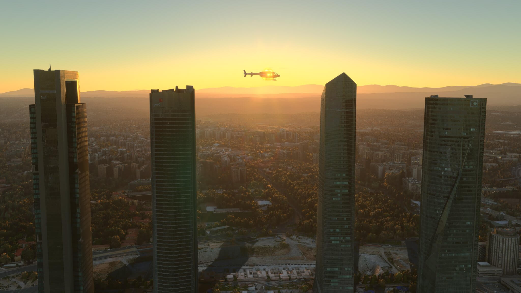 A Bell 407 Helicopter flies near a cityscape with the sun shining through the aircraft windows