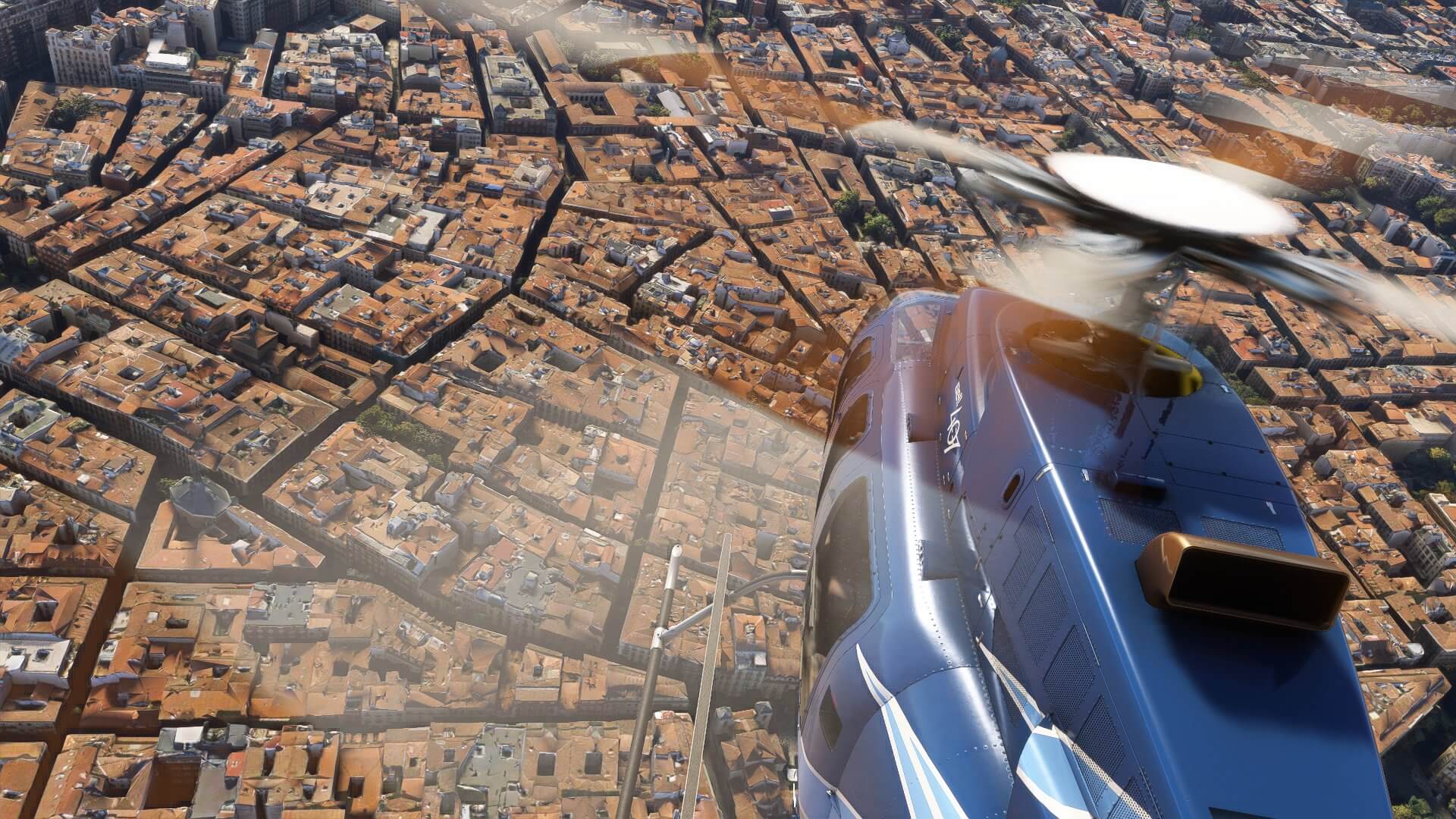 A Bell 407 helicopter flying above densely packed buildings in Barcelona, Spain