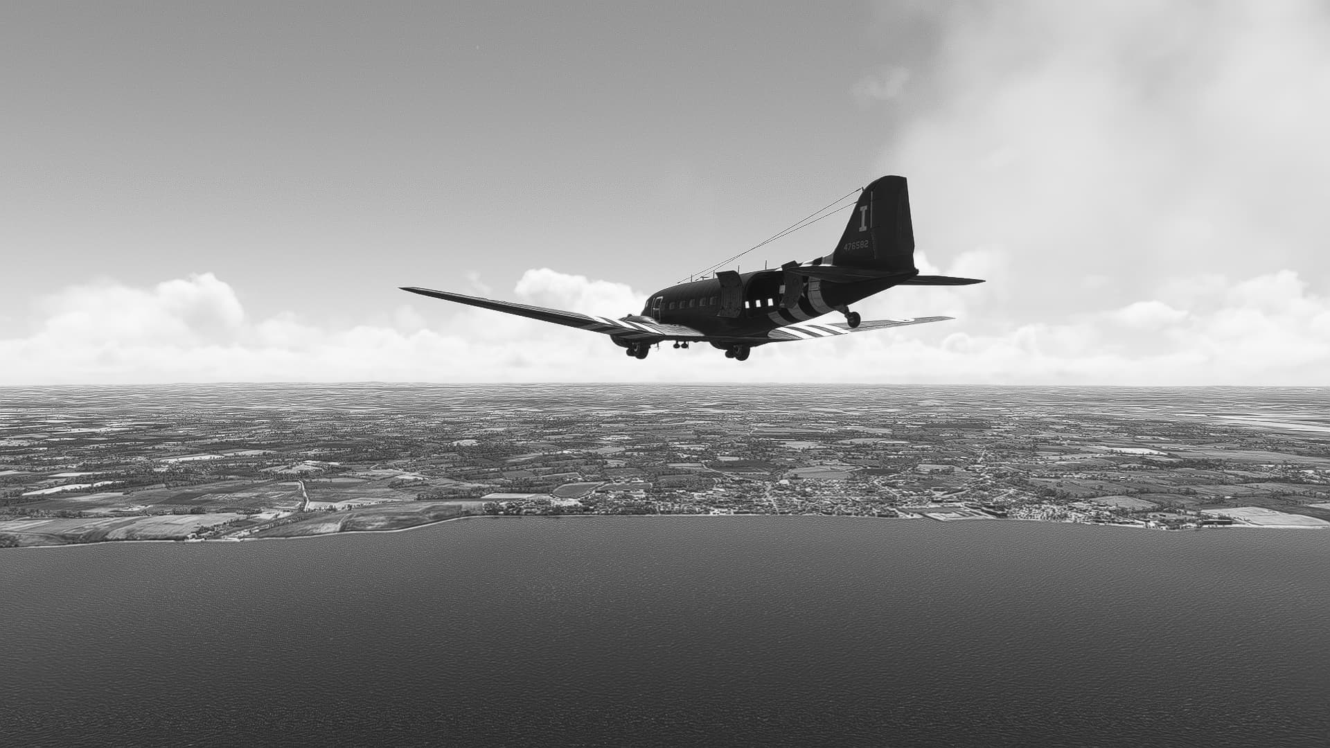 A C-47D flies toward the Normandy coast. The rear door is open. The image is in black and white.